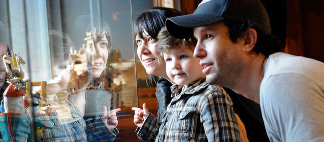 Family looking at a display, their reflection showing in the display glass