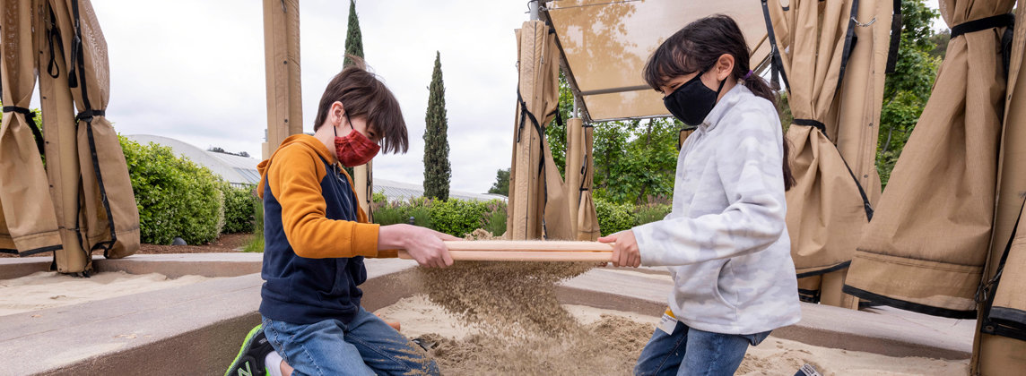 two kids sifting through dig pit