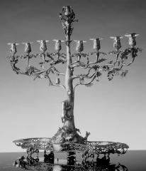 Silver menorah depicting a bear climbing a tree trying to reach the candle holders