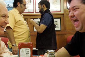 Two men sitting and laughing in a deli