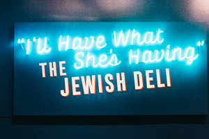 Blue wall with the words &quot;I&#039;ll Have What She&#039;s Having&quot; The Jewish Deli displayed on a neon sign