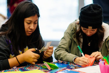 Two high school students creating artwork using magazine clippings and colorful paper