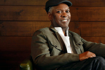 Photo of Booker T. Jones sitting in an armchair and smiling at the camera