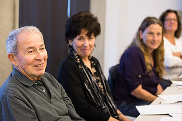 Adult students seated at a long table, listening to an instructor