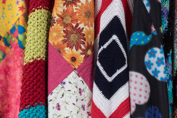 Photo of many colorful blankets hanging side by side across the frame