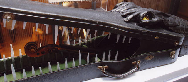 An alligator made out of a violin case and violin parts