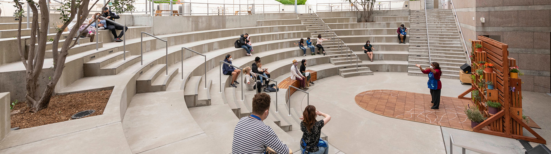 Photo of a group gathered in the outdoor amphitheater watching a presentation by a Skirball member