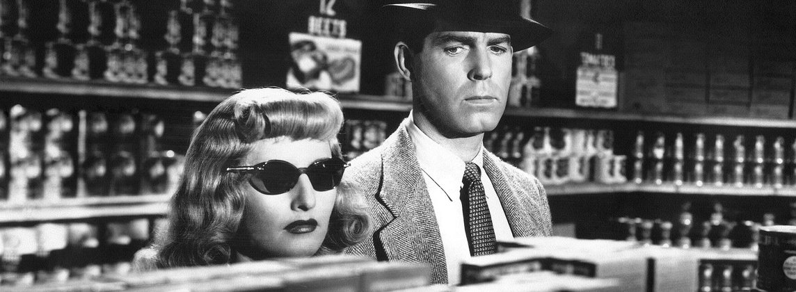 Black-and-white still from "Double Indemnity" of Barbara Stanwyck and Fred MacMurray looking serious in a store.