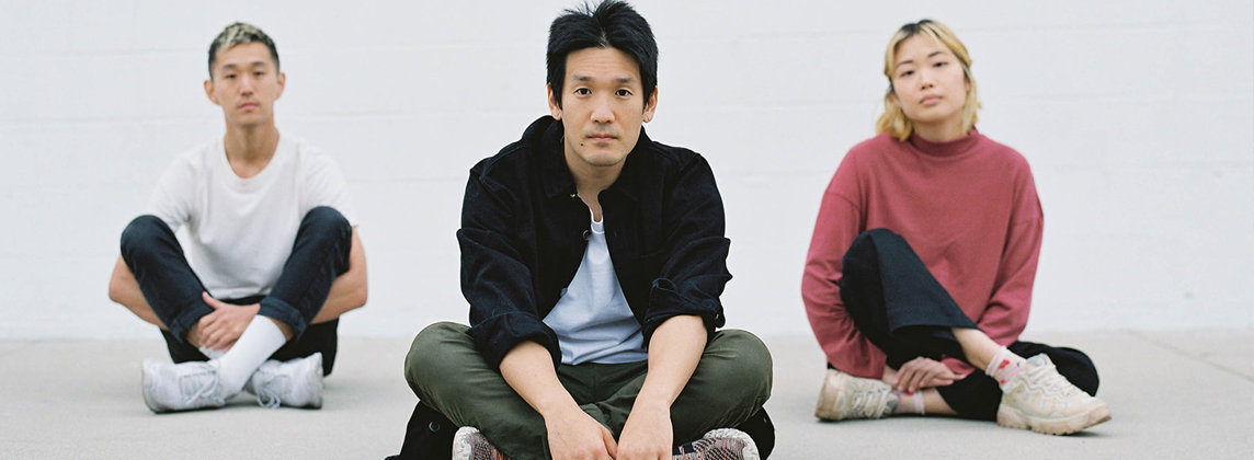 Three musicians sitting on the floor cross-legged in a triangle