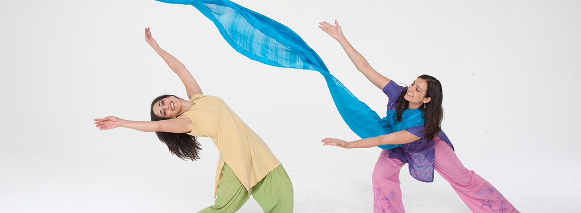 Photo of the Dancing Storytellers in colorful clothing posing with arms outstretched and a long, blue banner running from left to right