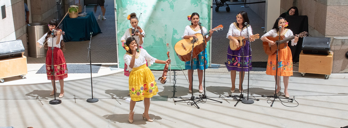Photo of Las Calibri standing in the Skirball Amphitheater performing with instruments