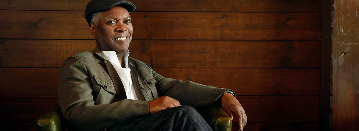 Photo of Booker T. Jones sitting in an armchair and smiling at the camera