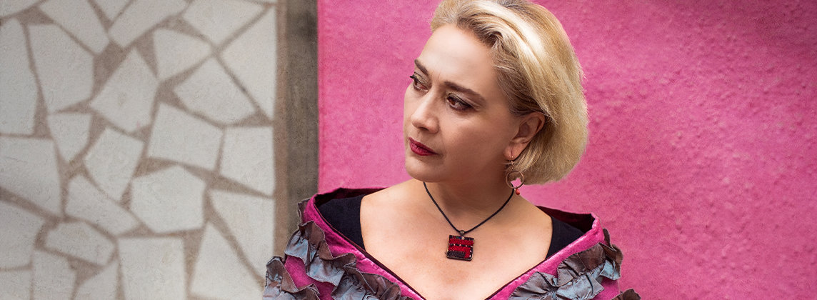Photo of Mamak Khadem standing in front of a pink wall looking away from the camera