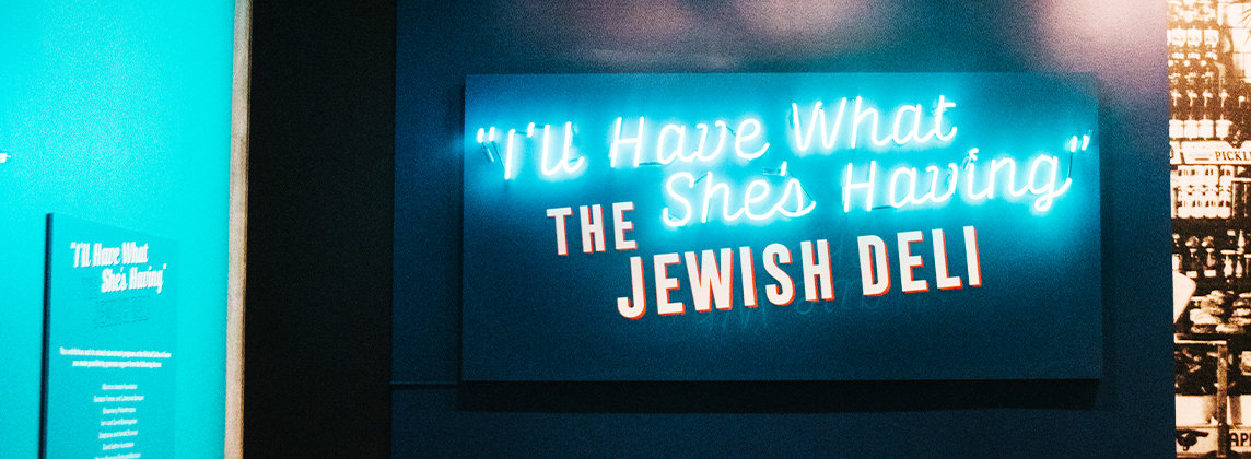 Blue wall with the words "I'll Have What She's Having" The Jewish Deli displayed on a neon sign