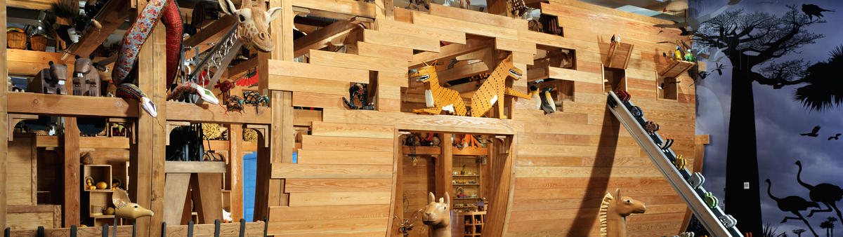 View of Noah's Ark with animals sticking their heads out from the ark and other animals going up a conveyor belt to the ark