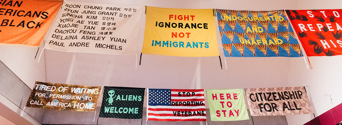 A series of colorful banners hanging from the ceiling in a gallery space