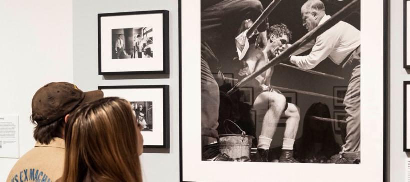 two visitors in gallery looking at photographs on the wall