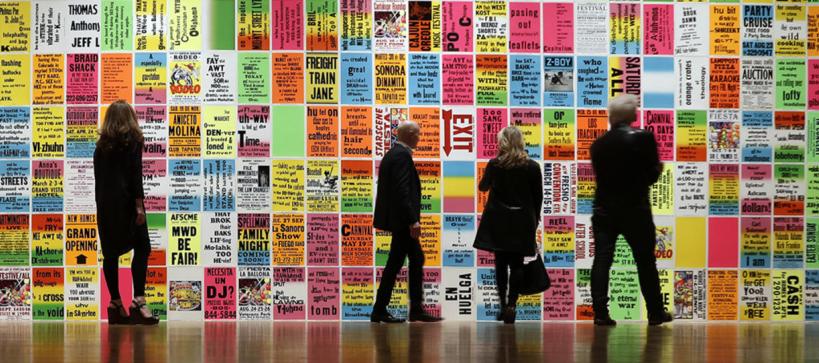 people looking at a wall filled with colored typography posters