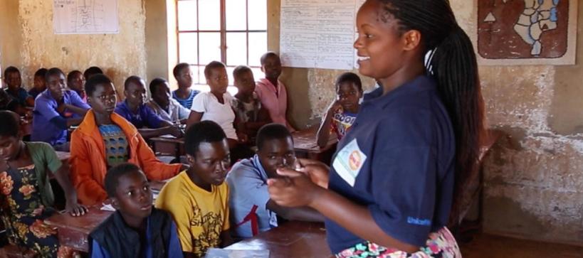 a female teacher standing in front of a class of students