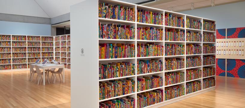 A gallery filled with book shelves of colorful books with names written on them.