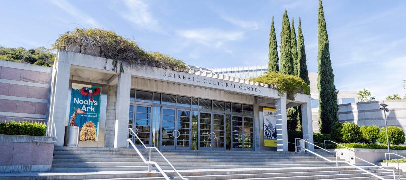 Front entrance to The Skirball Cultural Center, stairs that lead up glass doors.