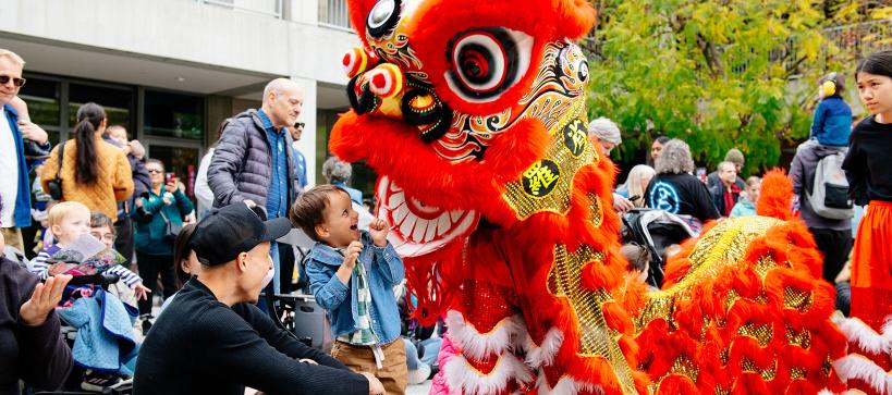 A child stares excitedly at a red dragon puppet in the courtyard.