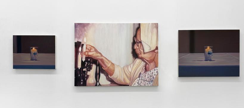 Three paintings on a gallery wall depicting candles with the one in the middle a person lighting one.