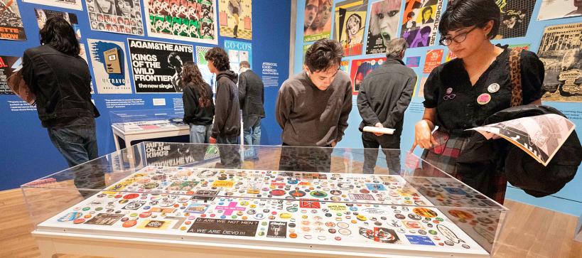 People in a gallery looking at various posters and pins.