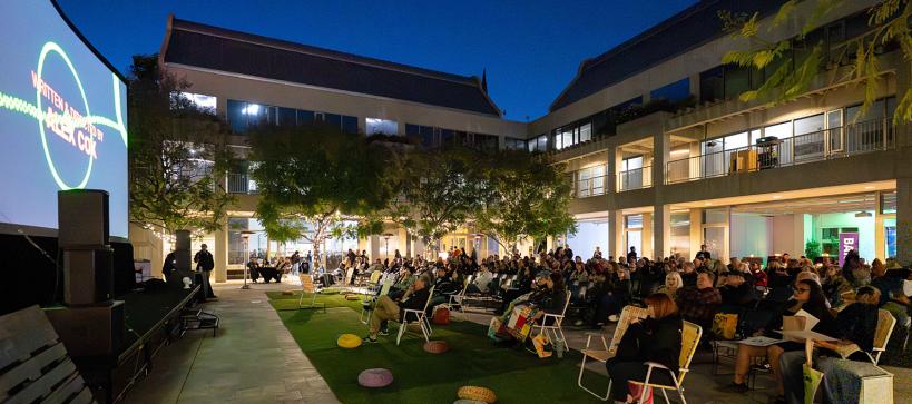 An outdoor movie plays while an audience watches.
