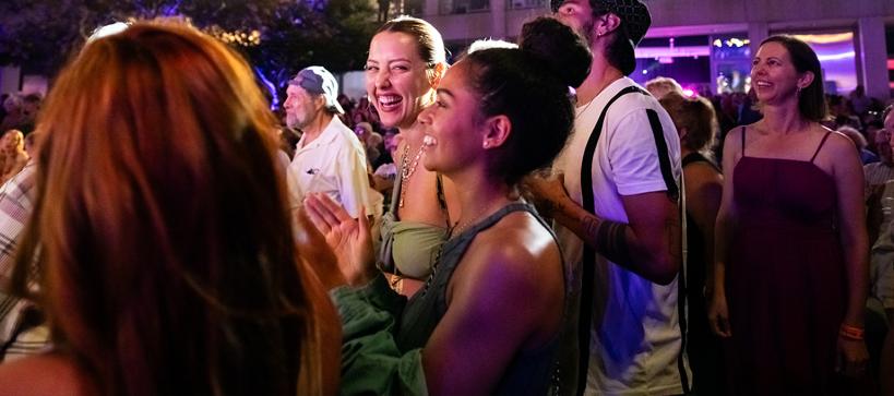People cheering a concert and one member looks and smiles at the camera.