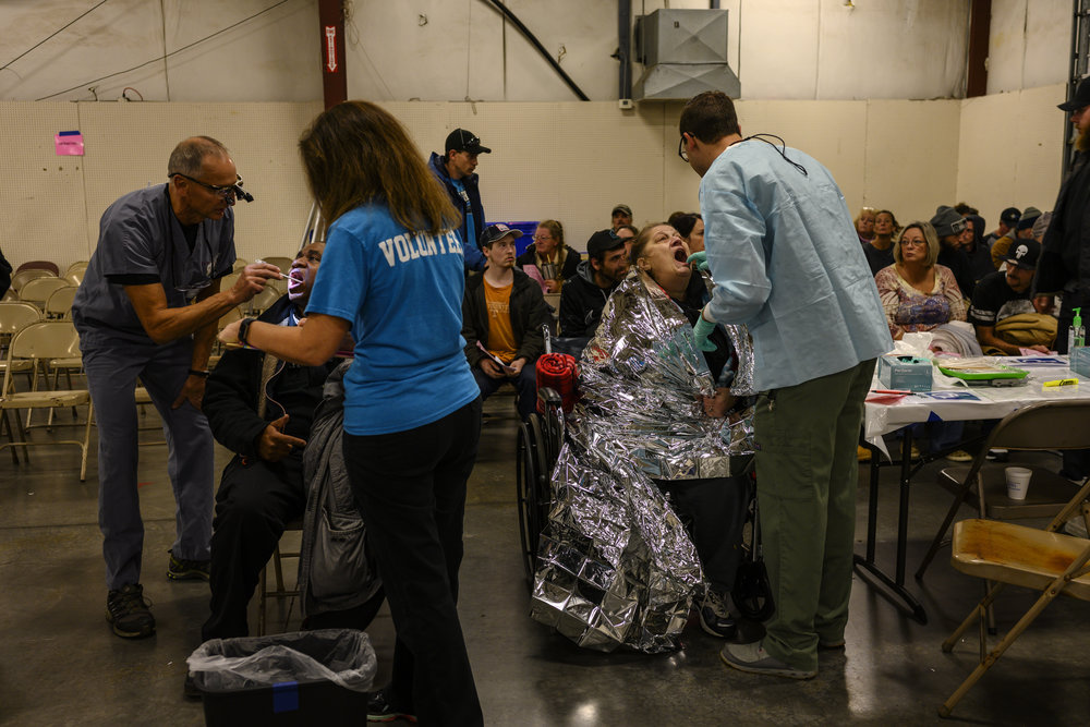The waiting room is crowded, and some of the people are swaddled in emergency blankets.