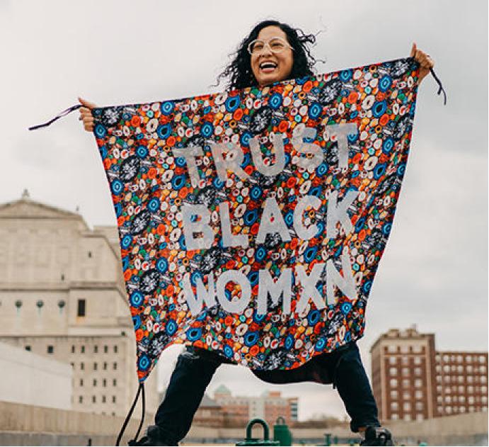 woman holding up a colorful banner that says 'Trust Black Womxn'