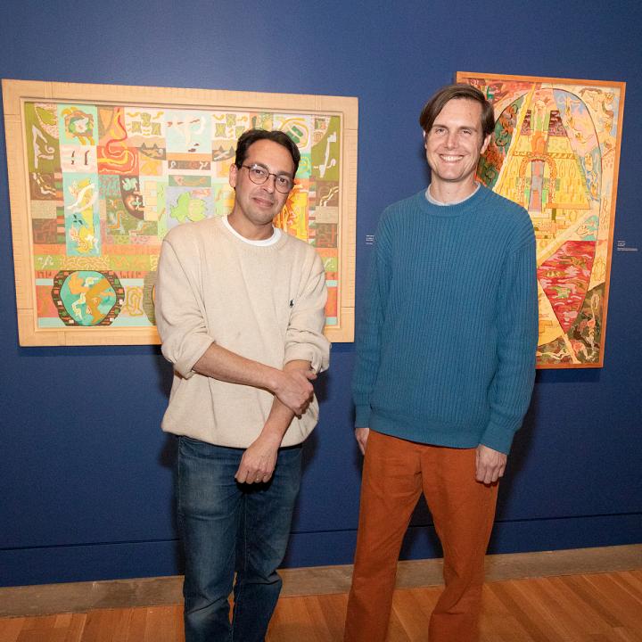 Two artist from Dub Lab standing in the Peter Krasnow exhibition gallery with two painting behind them