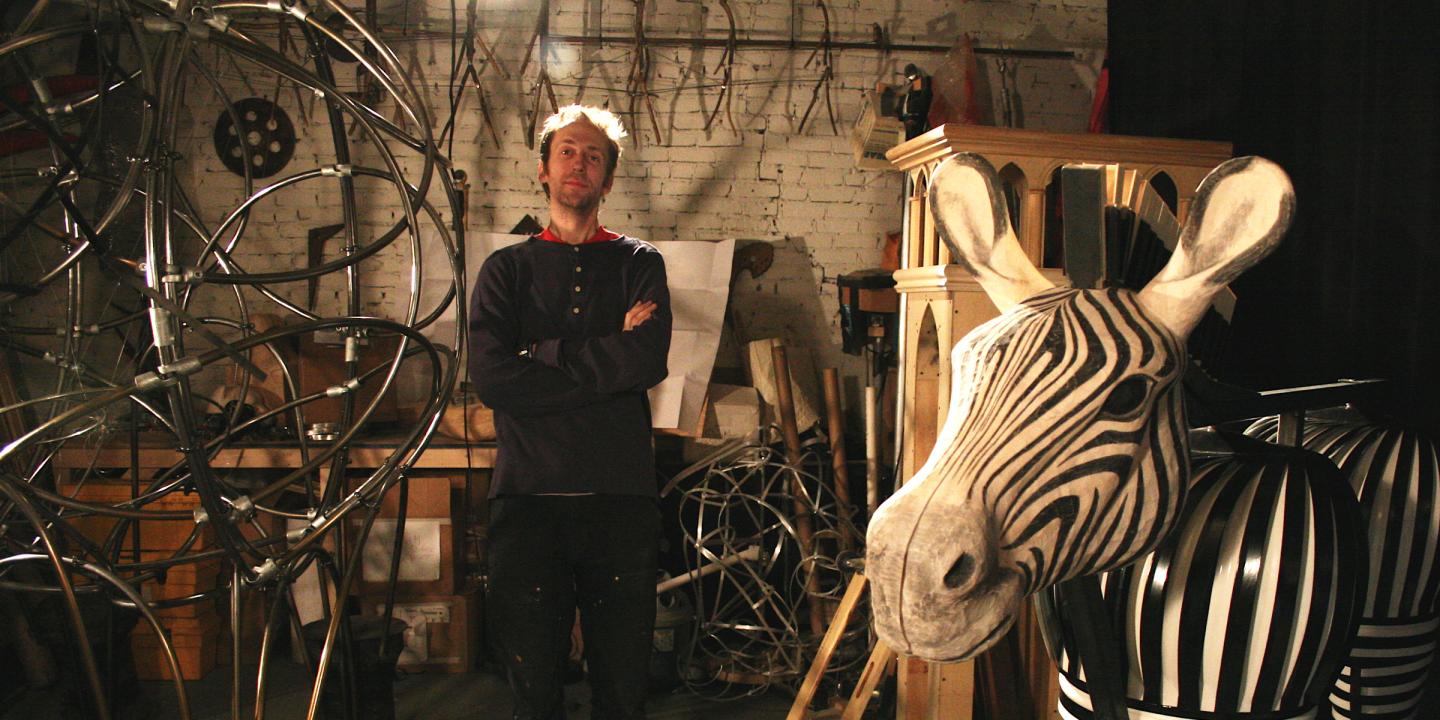 Artist Chris Green in artist studio standing next to materials that make the zebra and the elephant sculptures