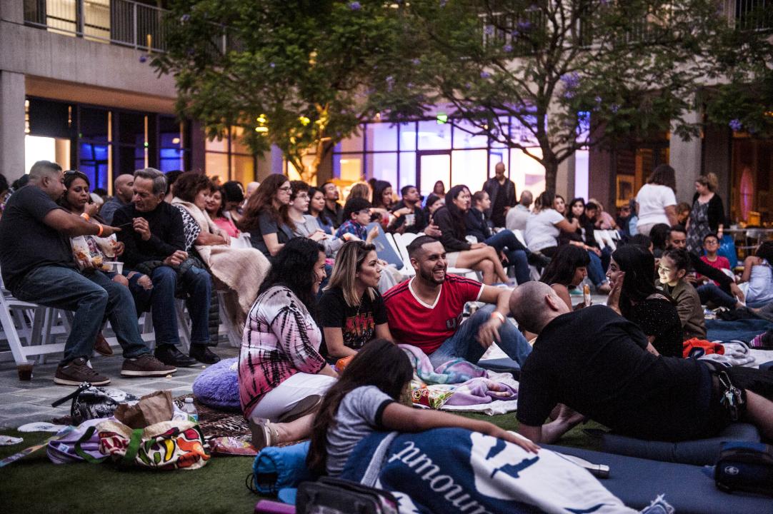 A large group of people sit in a courtyard laughing and talking.
