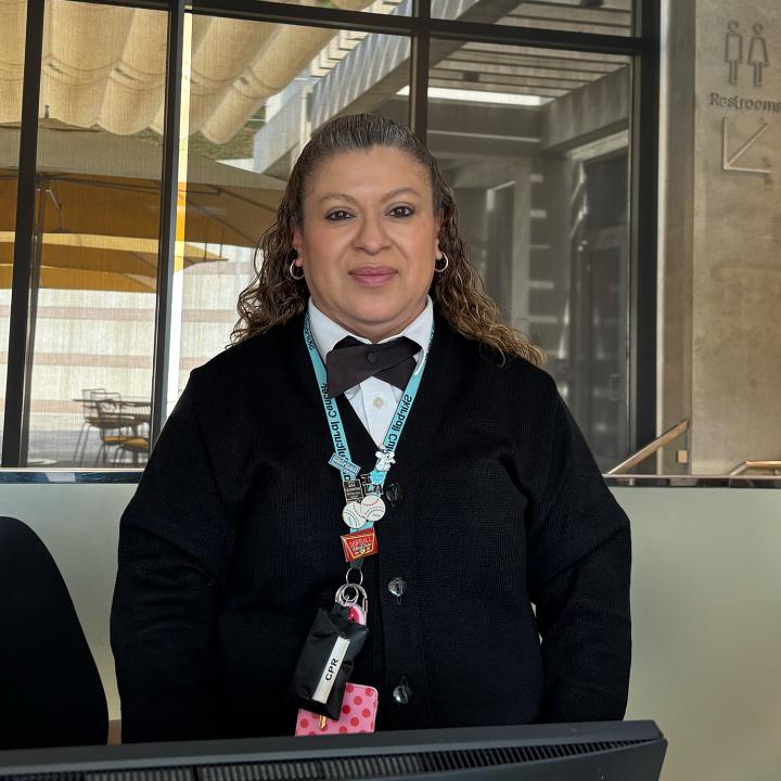 A woman standing at a front entrance desk smiling