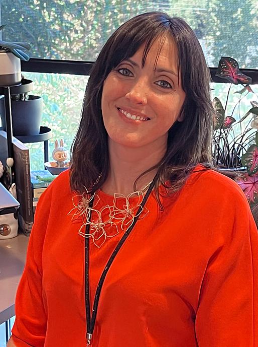 A woman smiles for a picture at her desk.