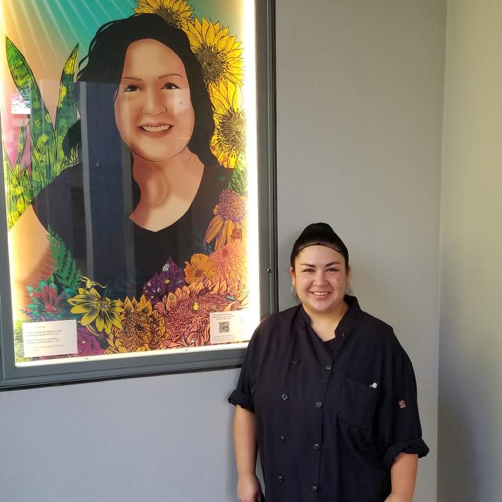 A woman poses next to an illustrated poster of herself.
