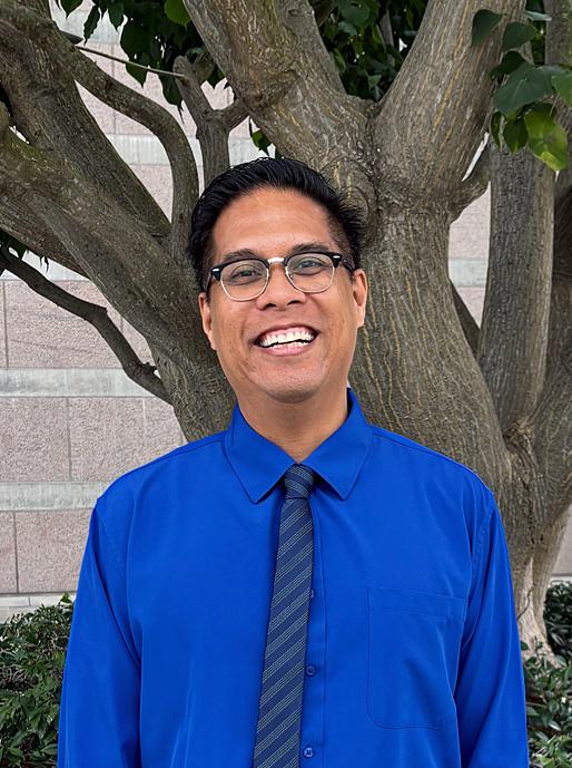 A headshot of a man wearing a tie smiling.