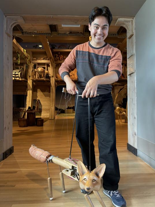 A man holding the strings of a fox puppet