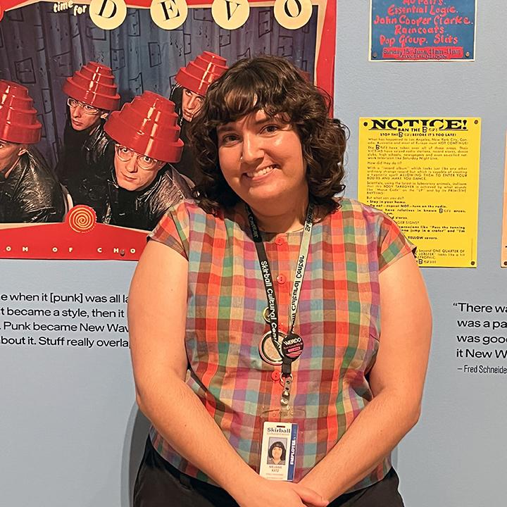 Woman stands in front of punk rock posters.