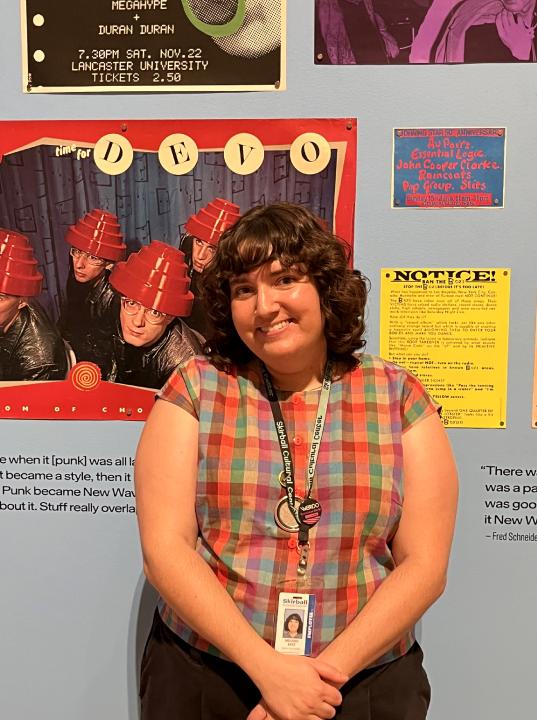 Woman stands in front of punk rock posters.