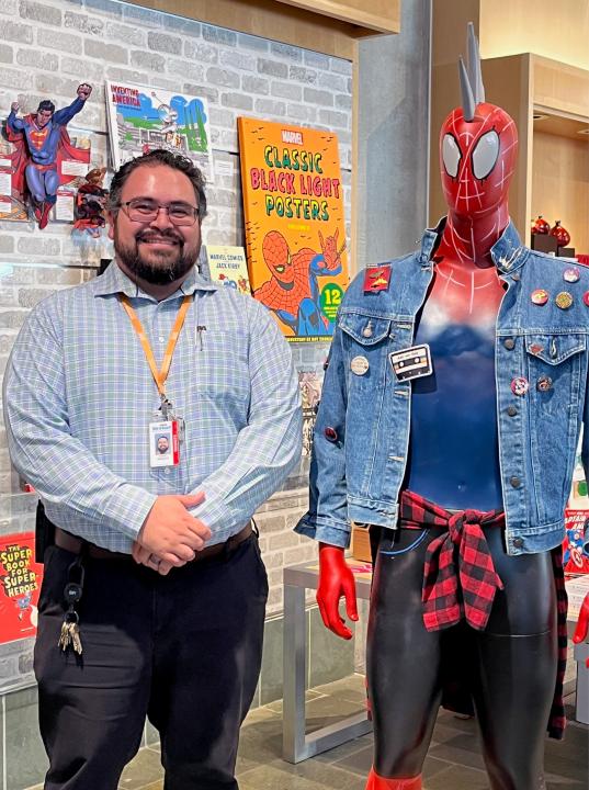 A man stands beside Spiderman mannequin 