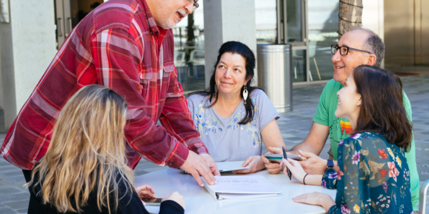 men and women gathered around a table having a discussion