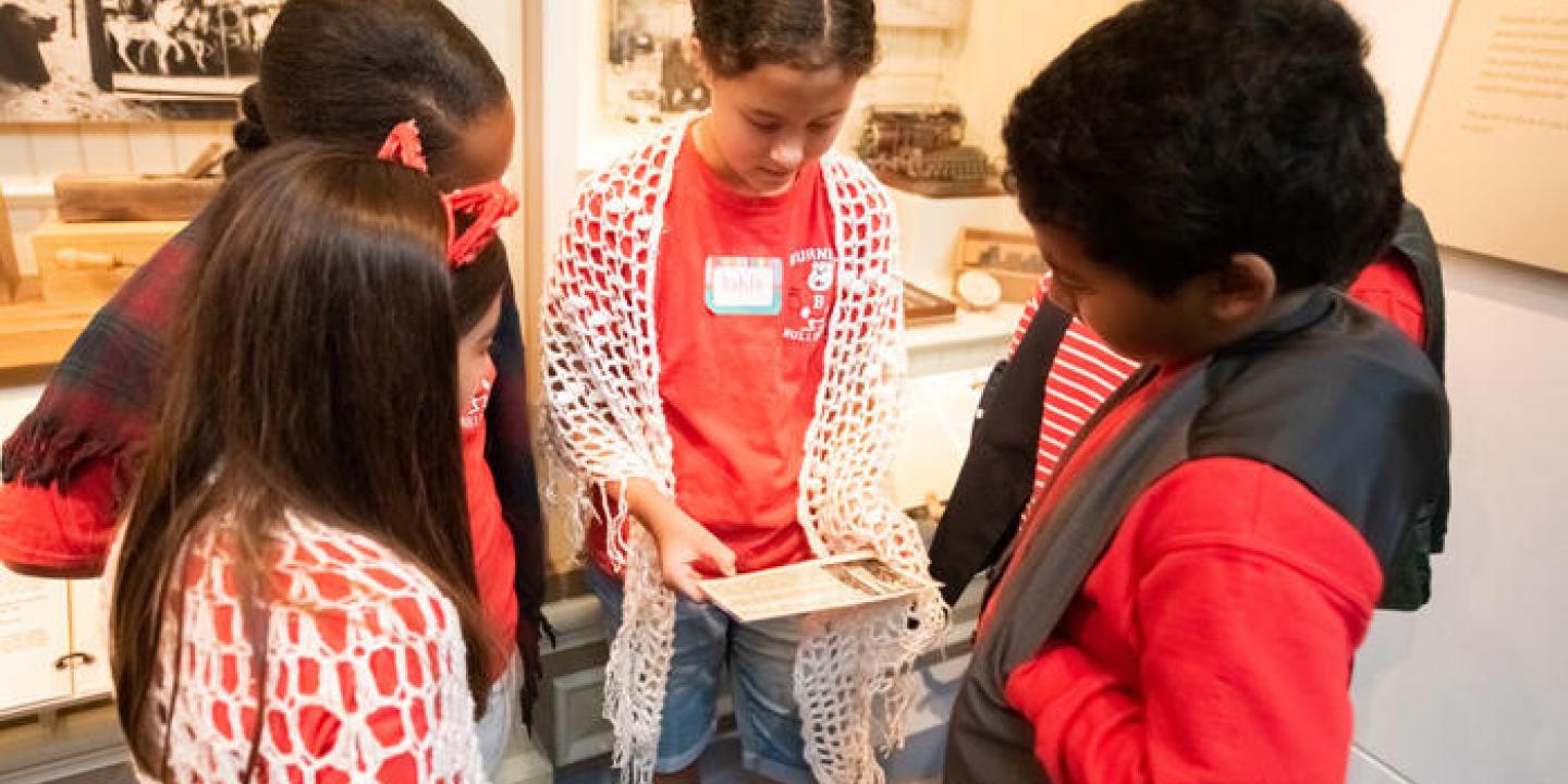 4 young students look at a card with text on it