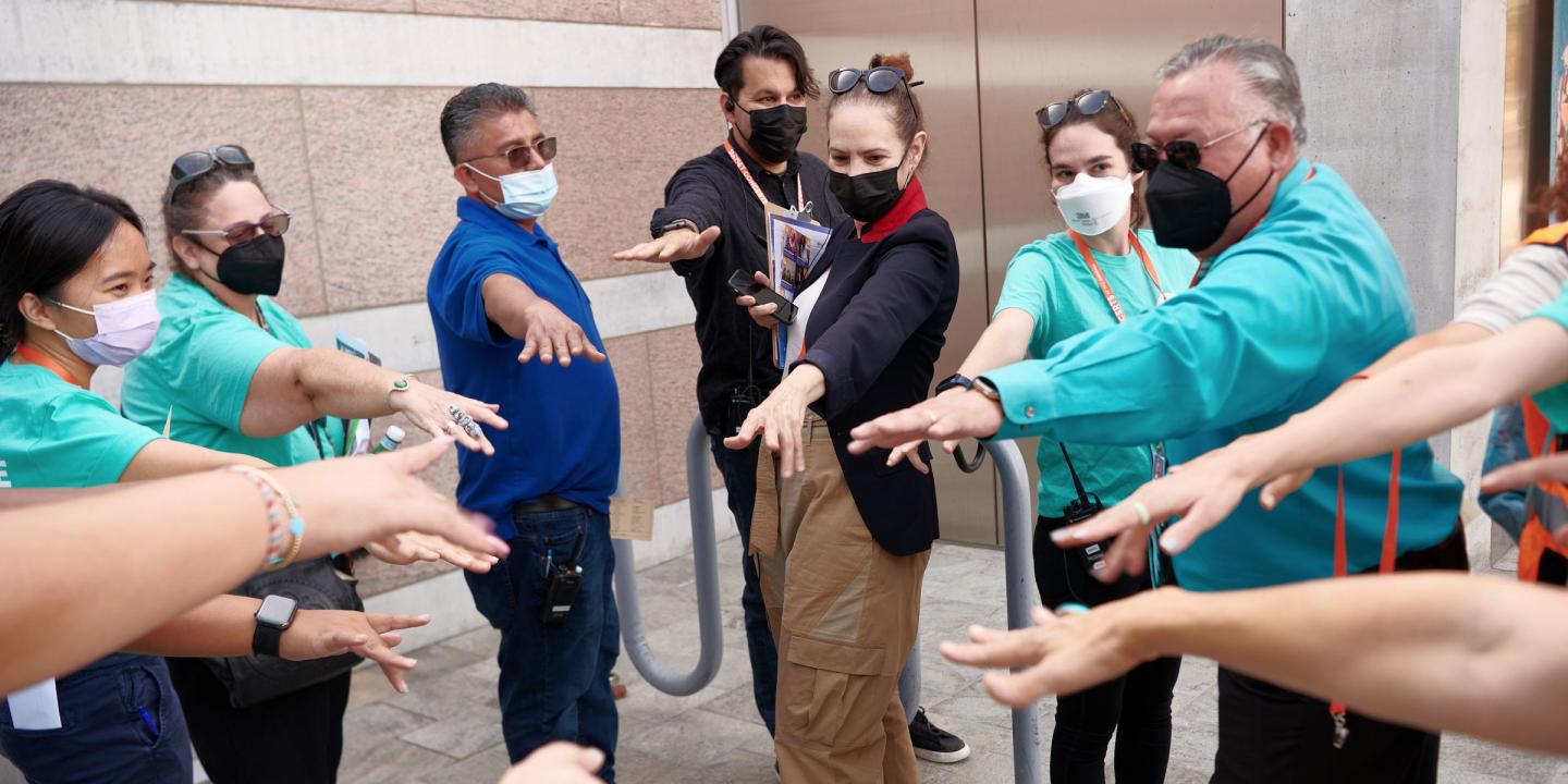 a group of Skirball employees standing in a circle with arms stretched toward center getting ready for a performance