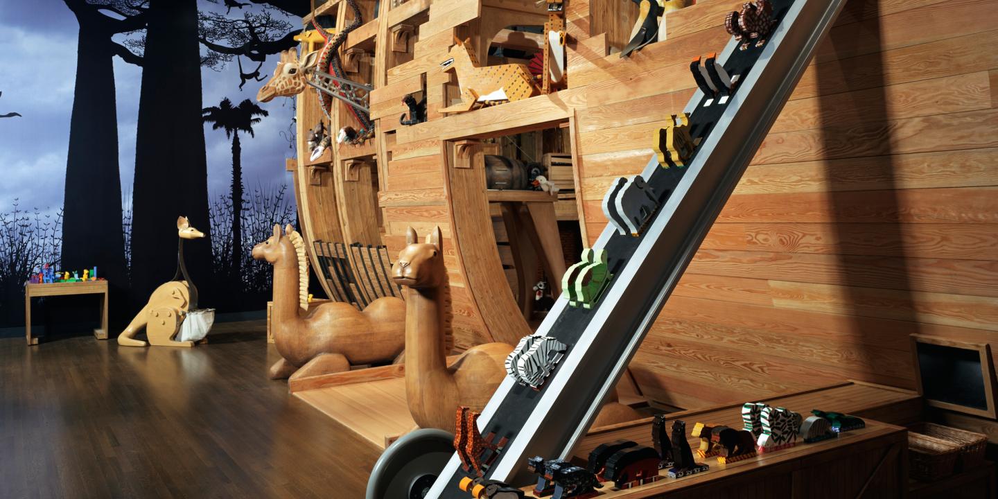Image of the Noah's Ark exhibition build from wood and craved animals showing a conveyer belt that transports small animals up the ark
