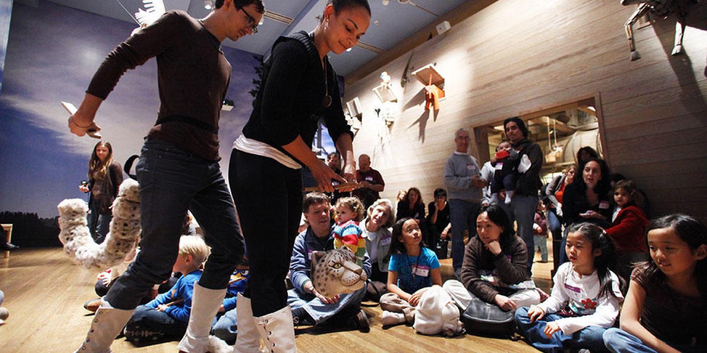 puppeteers acting in front of a group of children seated on the floor in front of Noah's Ark