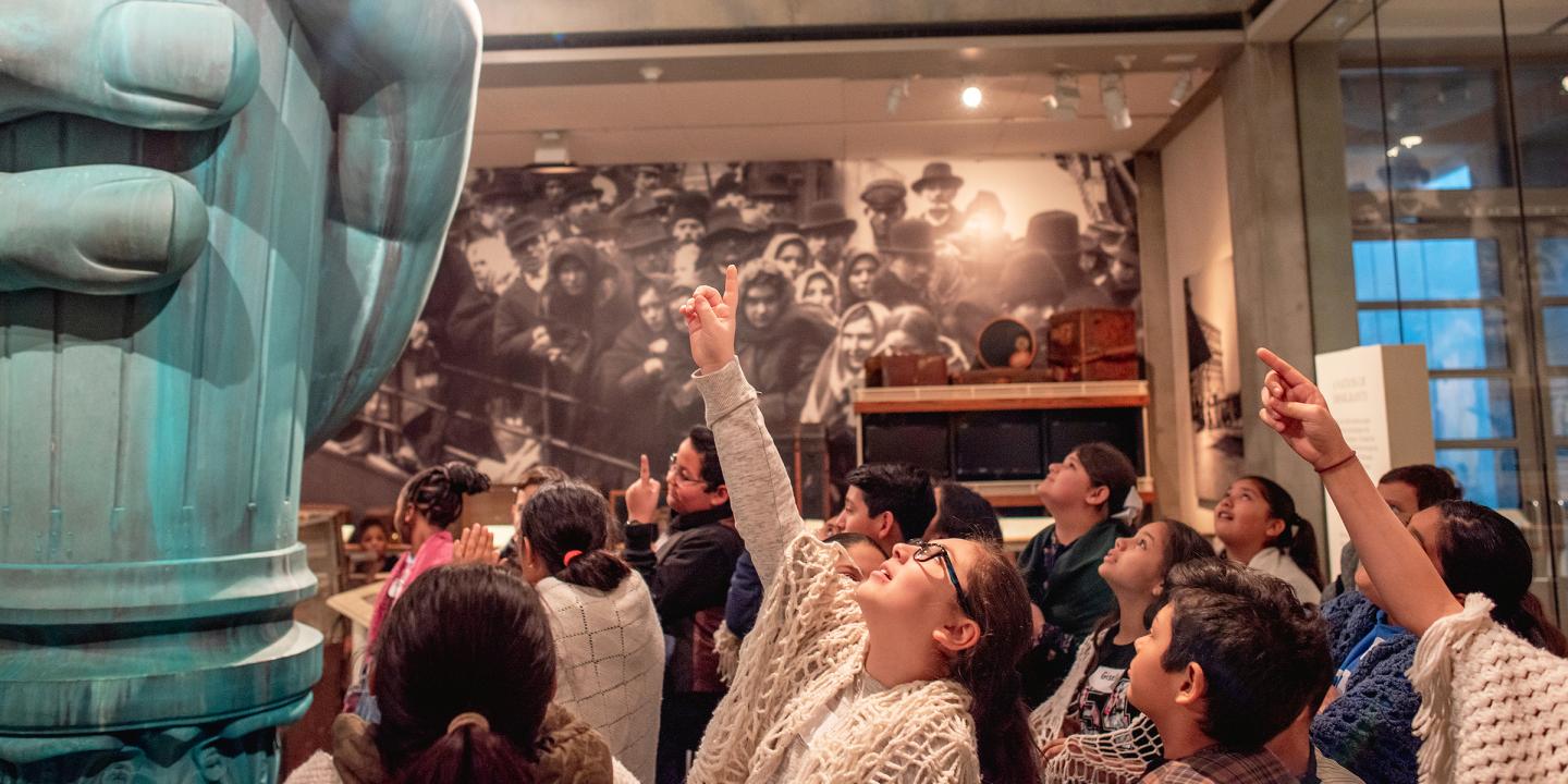 A group of school children looking up at the statue of liberty hand in the Vision and Values gallery