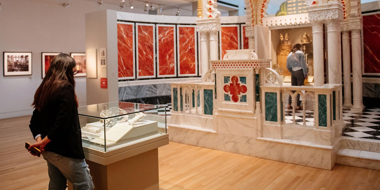 A women looking at case with objects in it in a large gallery.